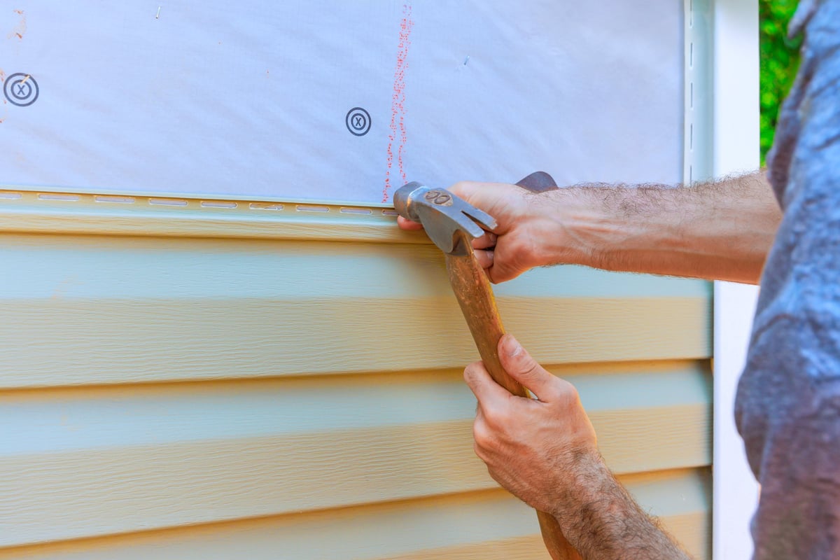 Worker securing new PVC vinyl siding