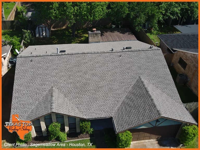 Aerial view of residential house with gray shingle roof, surrounded by green trees in Houston, Texas neighborhood