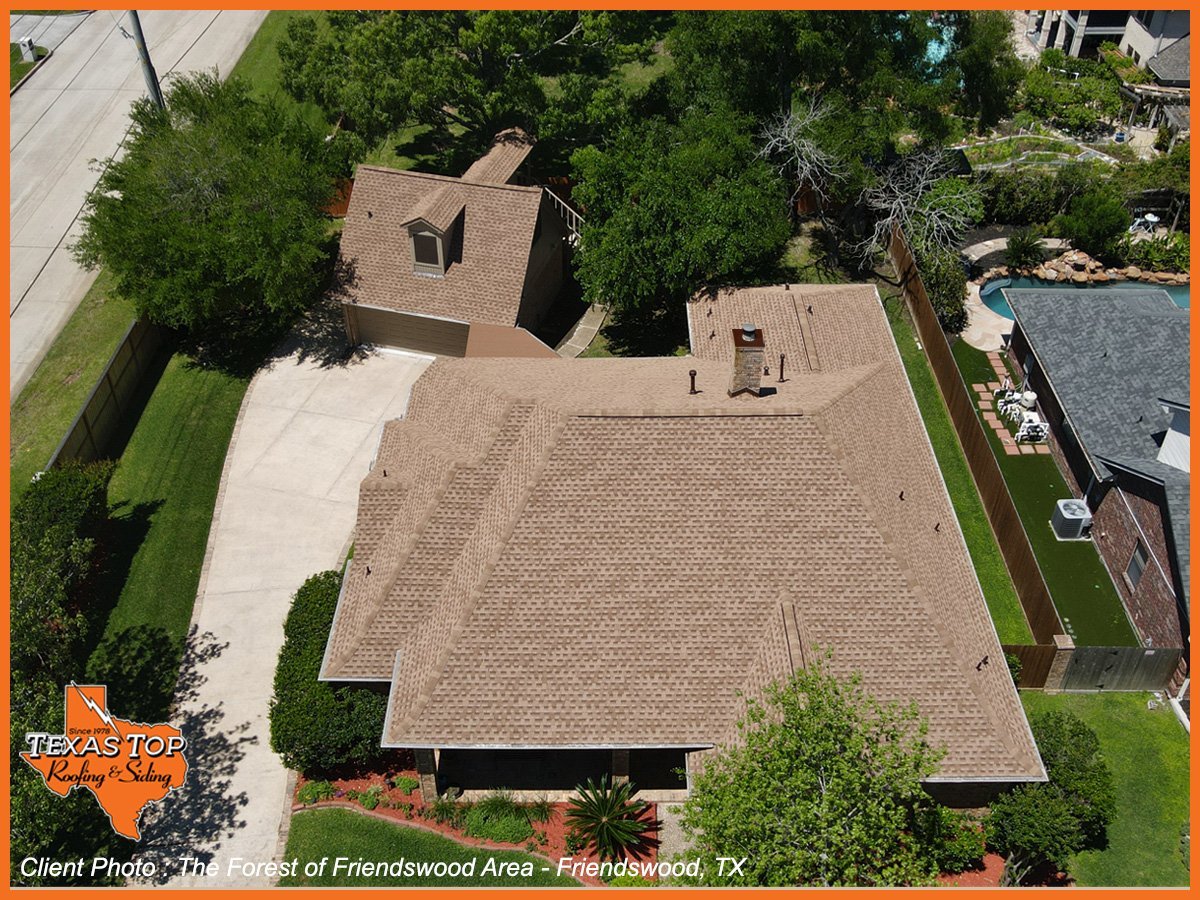 Aerial view of brown brick residential home with large shingled roof